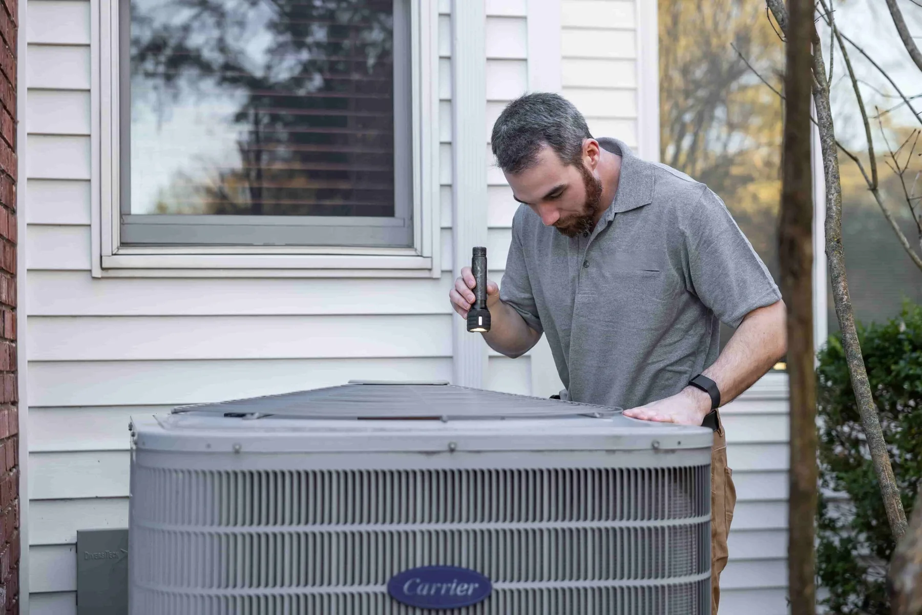 Technician inspecting a Carrier heat pump installed at a home